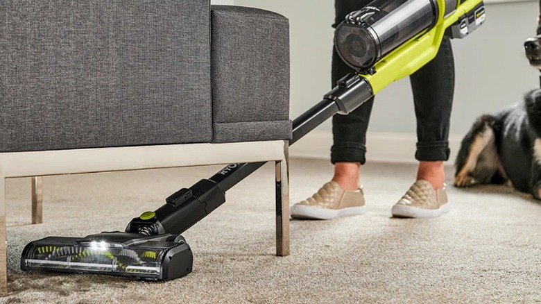 Ryobi One+ HP 18V Cordless Pet Stick Vacuum Cleaner cleaning carpet under chair