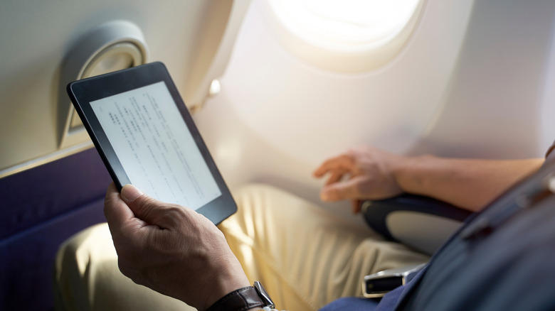 man using eReader in plane
