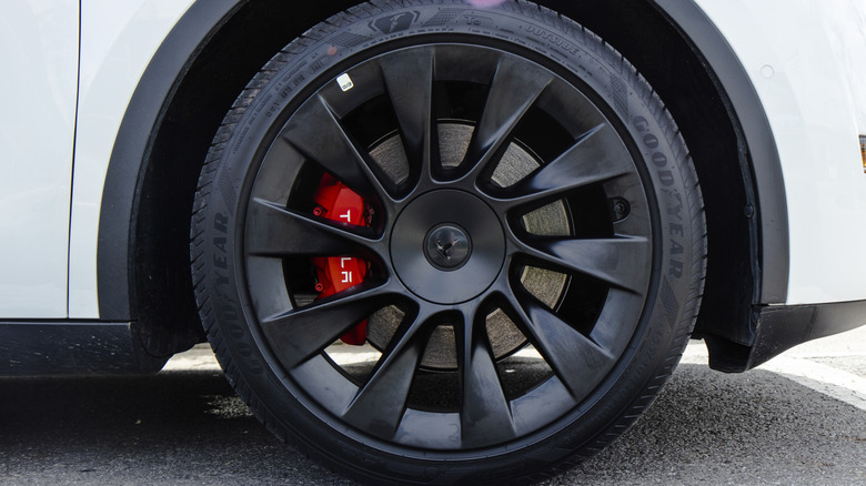A white Tesla with red brake calipers, fitted with Goodyear tires.