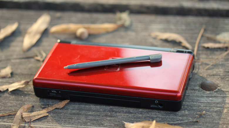 A red Nintendo DS lite on display outside with its stylus lying on top of it