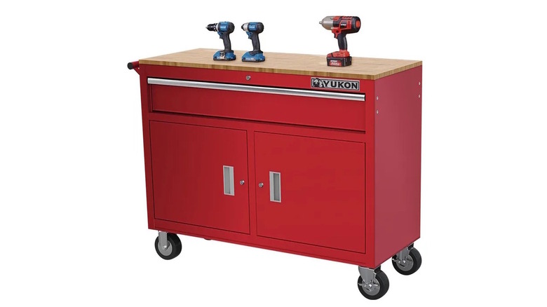 red workbench with wood top and drills on bench