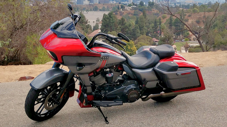 Red and black 2018 Road Glide view from the front with a city and forest backdrop