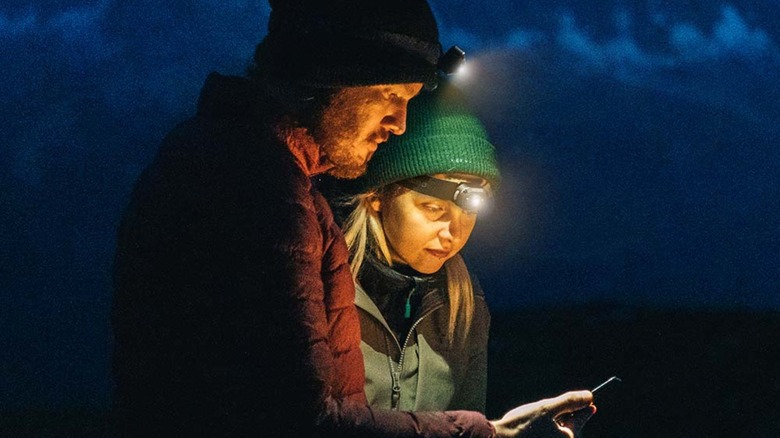 Two people in the dark outside with headlamps on