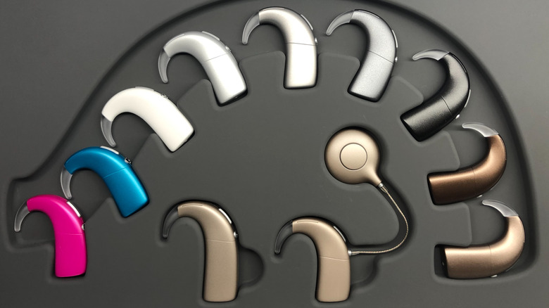 A set of Oticon hearing aids in their special box, each different colors with several attachments.