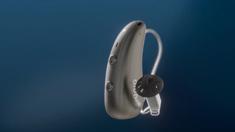 A silver-golden Signia hearing aid 3D model placed against a navy blue studio backdrop.