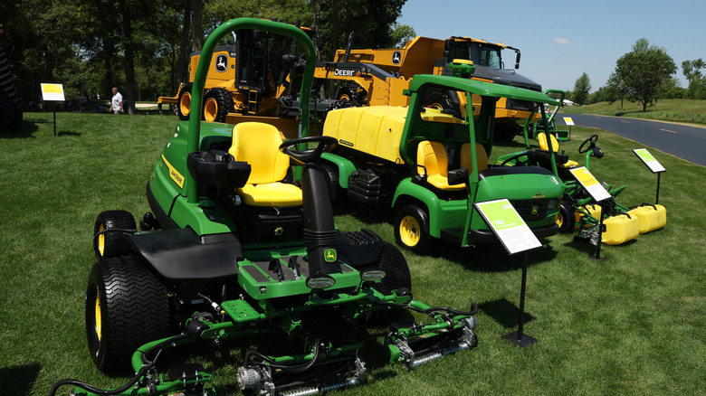 Some John Deere equipment in the grass by a road