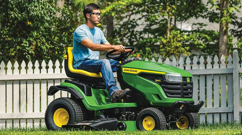 A John Deere S160 being driven by a man in a lawn