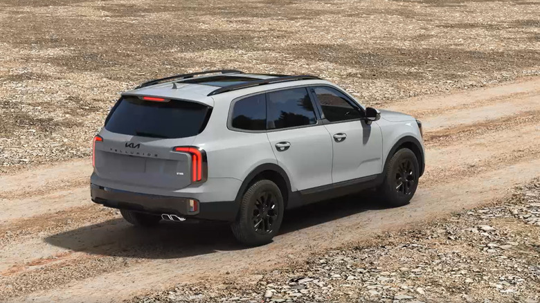 A gray Kia Telluride on a dirt road from behind