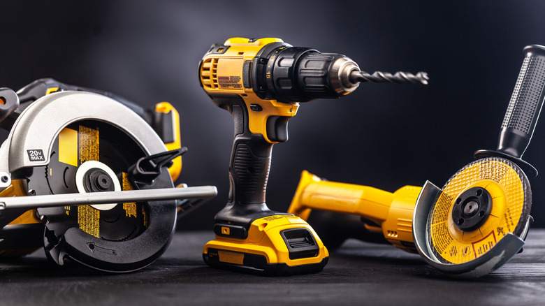 selection of yellow construction tools: a saw, a drill, and a grinder