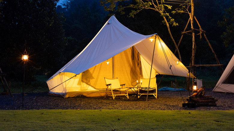 A lit-up tent with two chairs underneath of it