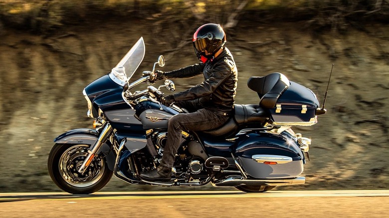 A man in full attire riding a Kawasaki 1700 Vulcan down a road at speed