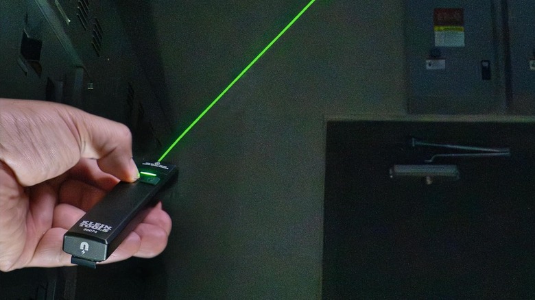 A person holding flashlight with green laser