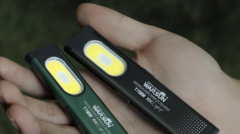 A person holding a pair of pocket flashlight