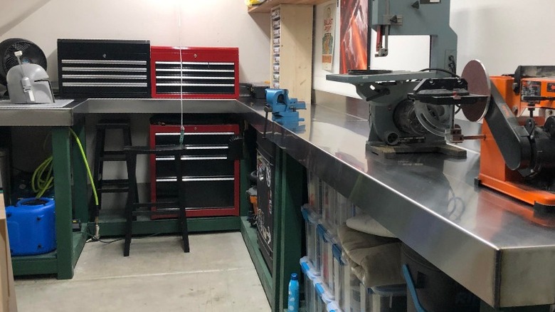 Wrap around work bench topped in sheet metal with tools in garage