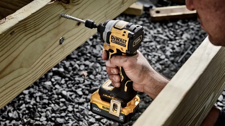 Person driving fastener into floor framing