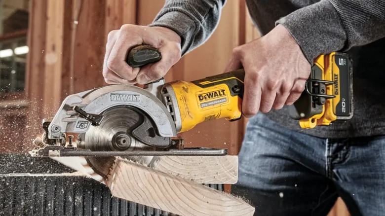 Person cutting 2x6 with a DeWalt Atomic 20V Max 4 ½-inch Circular Saw
