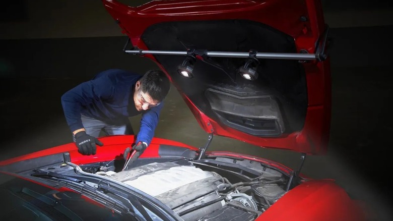 Icon 2,100-lumen LED Rechargeable Magnetic Compact Floodlights attached to inner car hood as mechanic works on engine