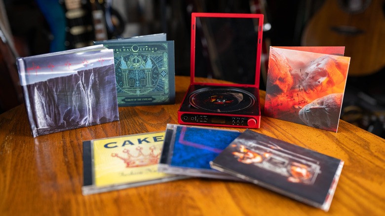 A red FiiO DM15 on a wooden table surrounded by CDs and CD booklets.