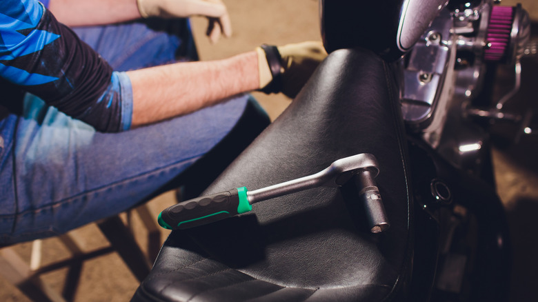 A mechanic changing parts of a bike, their wrench laid atop the seat