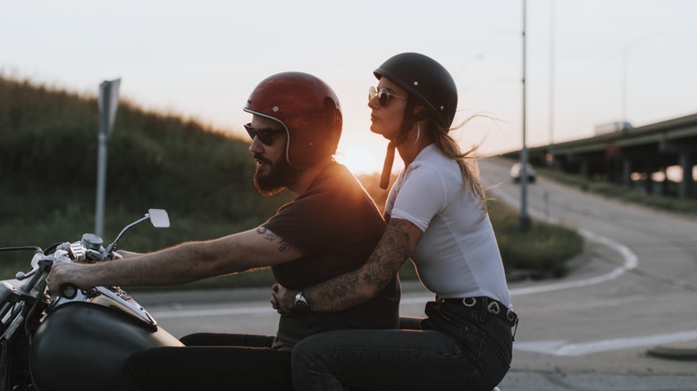 A man and woman riding two-up on a sunset motorcycle ride.