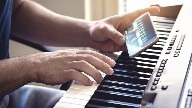 Person holding smartphone and playing keyboard