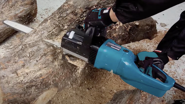 Cahinsaw cutting through a tree trunk