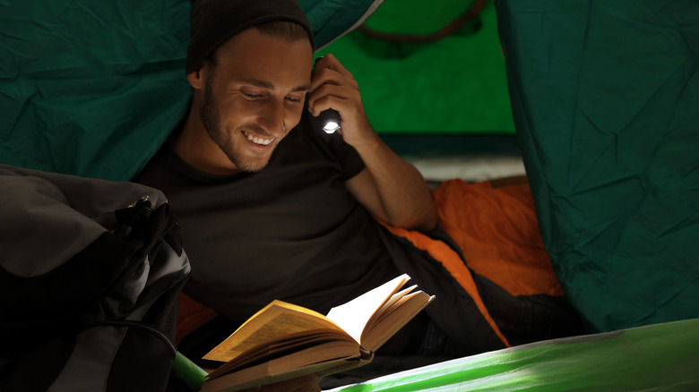 Man uses a flashlight to read