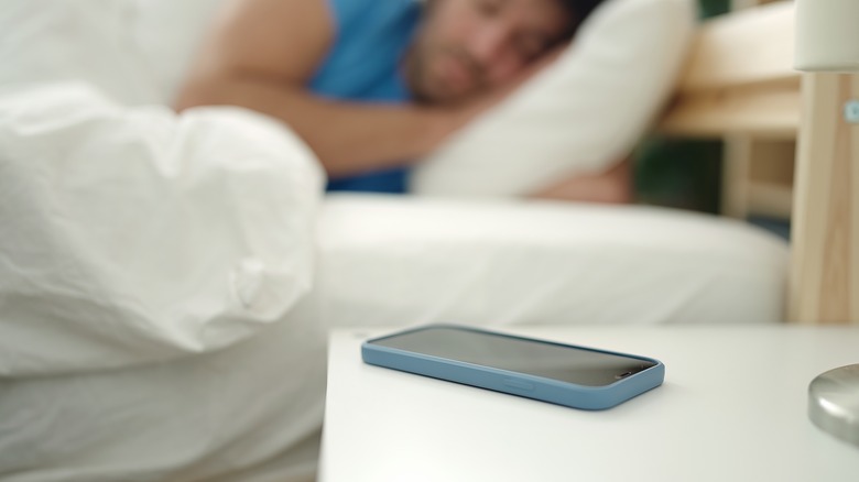 Man sleeping phone bedside table