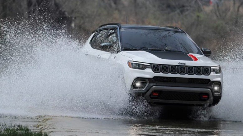 A white Jeep Compass driving through a puddle