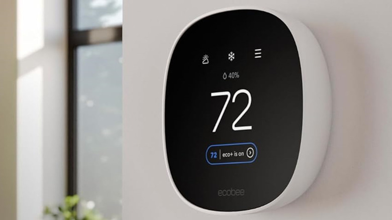 Ecobee Thermostat on thee side of a wall, with a light coming through the window