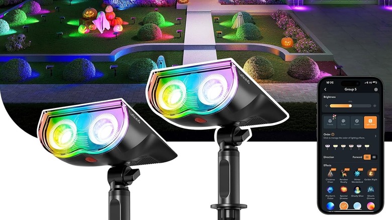 A pair of Linkind Smart Solar Spot Lights with a fully light backyard behind them