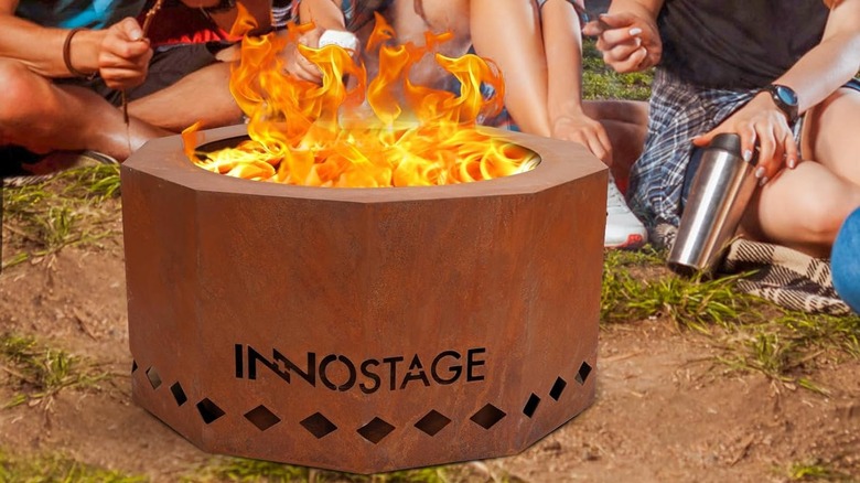 Bronze fire pit with fire going at the center, surrounded by sand