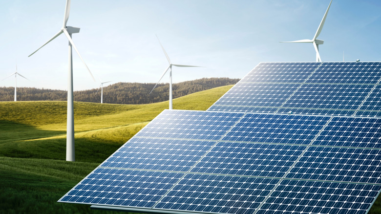 Solar panels and wind turbines installed on green hills