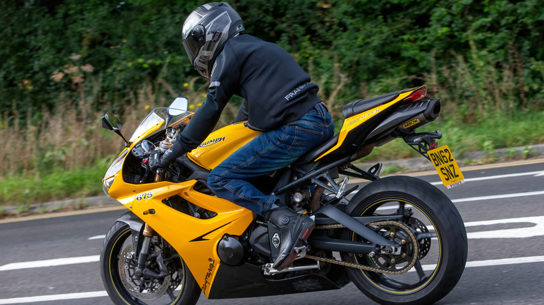 Man riding a 2012 yellow Triumph Daytona 675 motorcycle travelling on a British road