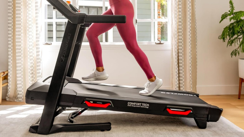 A Bowflex BXT8J in a living room with a person running on it.