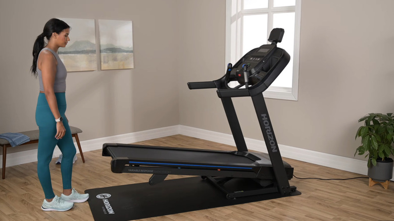 A person in front of an Horizon treadmill inside a house.
