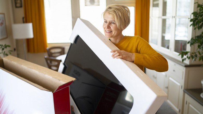 A woman unwraps her delivery of a new smart tv.