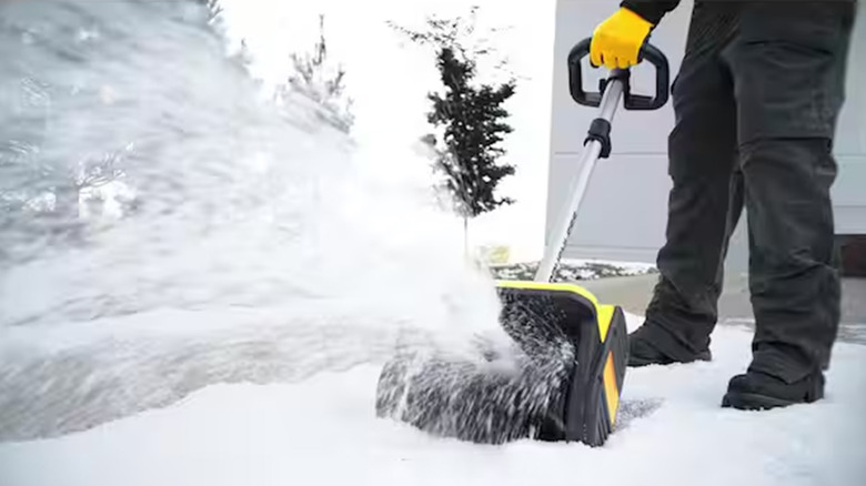 A person using a snow shovel to clear their driveway