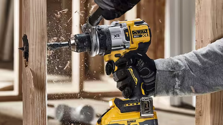 A man drilling a hole in a piece of wood with a DeWalt Hammer Drill