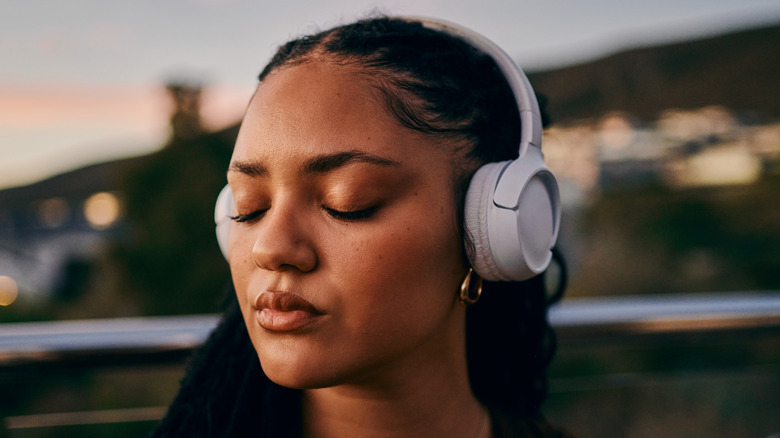 Close-up of a woman enjoying music outside while wearing headphones