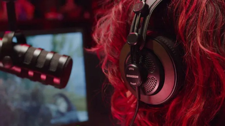 Close-up of a woman in front of a microphone and wearing Samson SR850 headphones