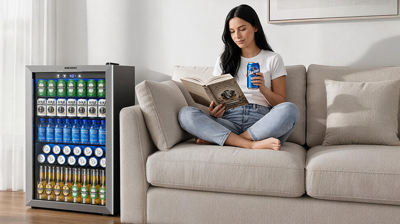 woman drinking beer on couch next to refrigerator