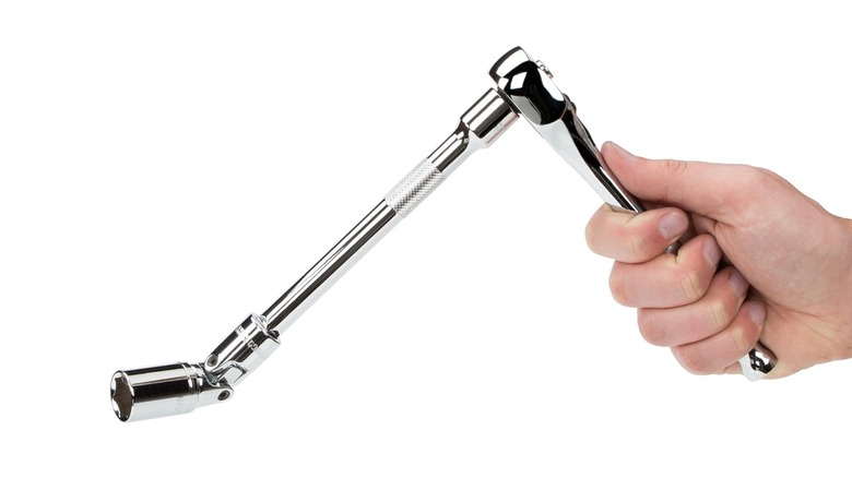 A hand uses a universal joint socket with a ratchet and an extension