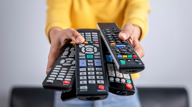 person holding a lot of remotes