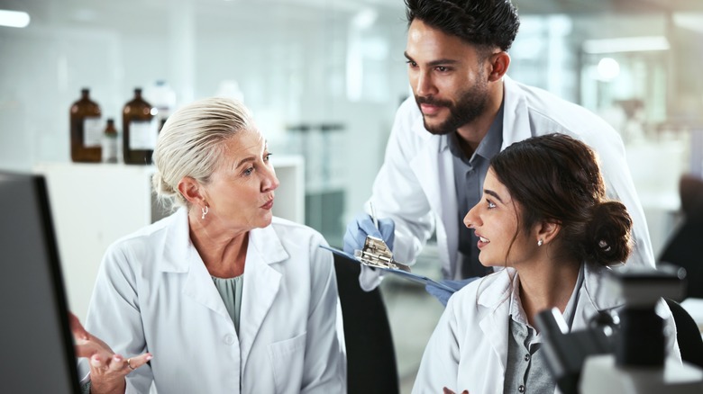 three researchers in lab coats talking