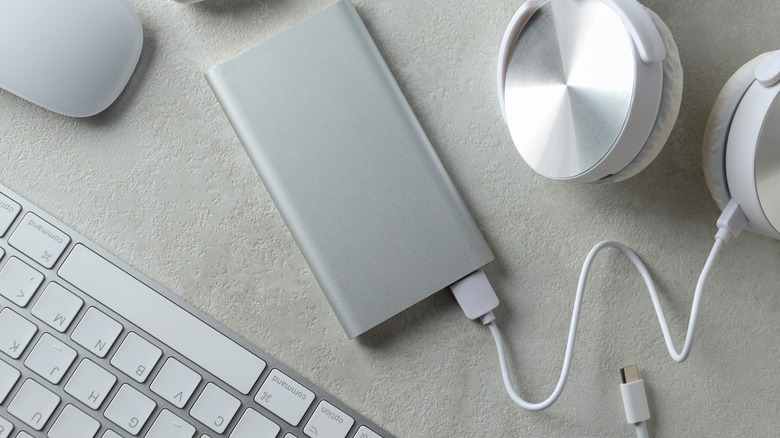 A person holding an iPhone with the Sharge Disk Pro attached to it via MagSafe