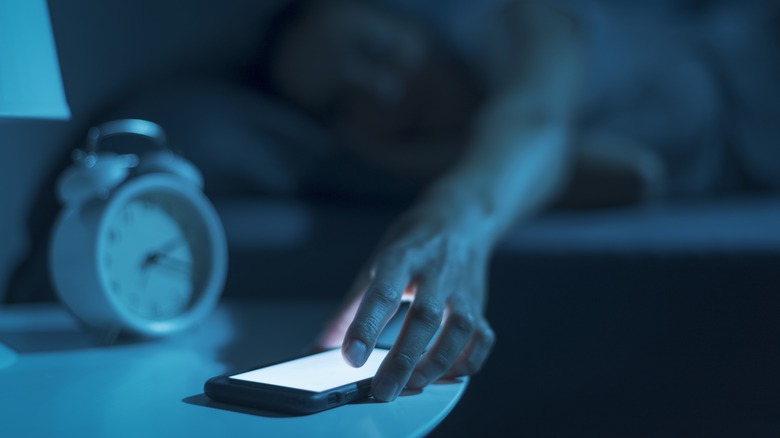 woman grabbing phone from bed