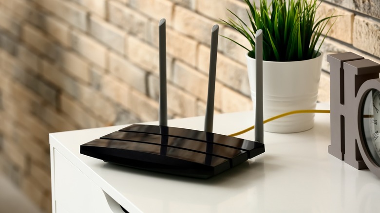 Black Wi-Fi router on a white TV console