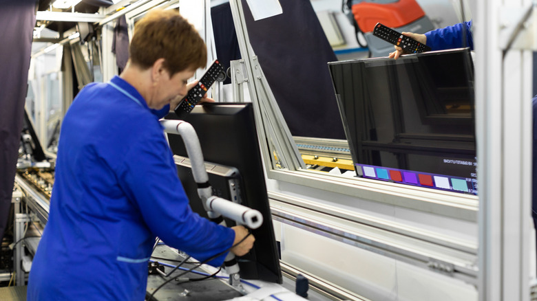 Woman assembling television in factory