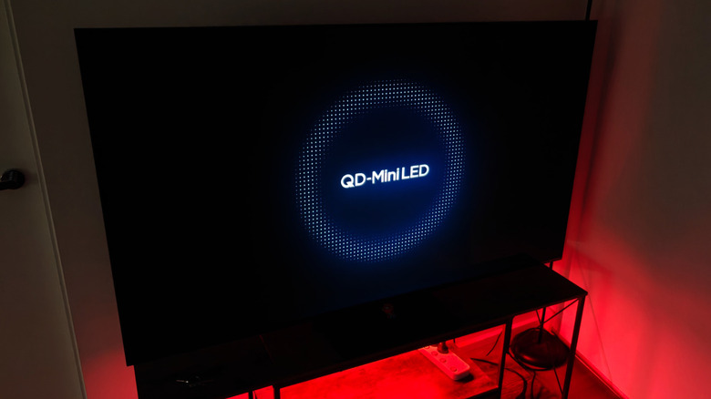 Mini LED TV on a stand, red lighting in the background